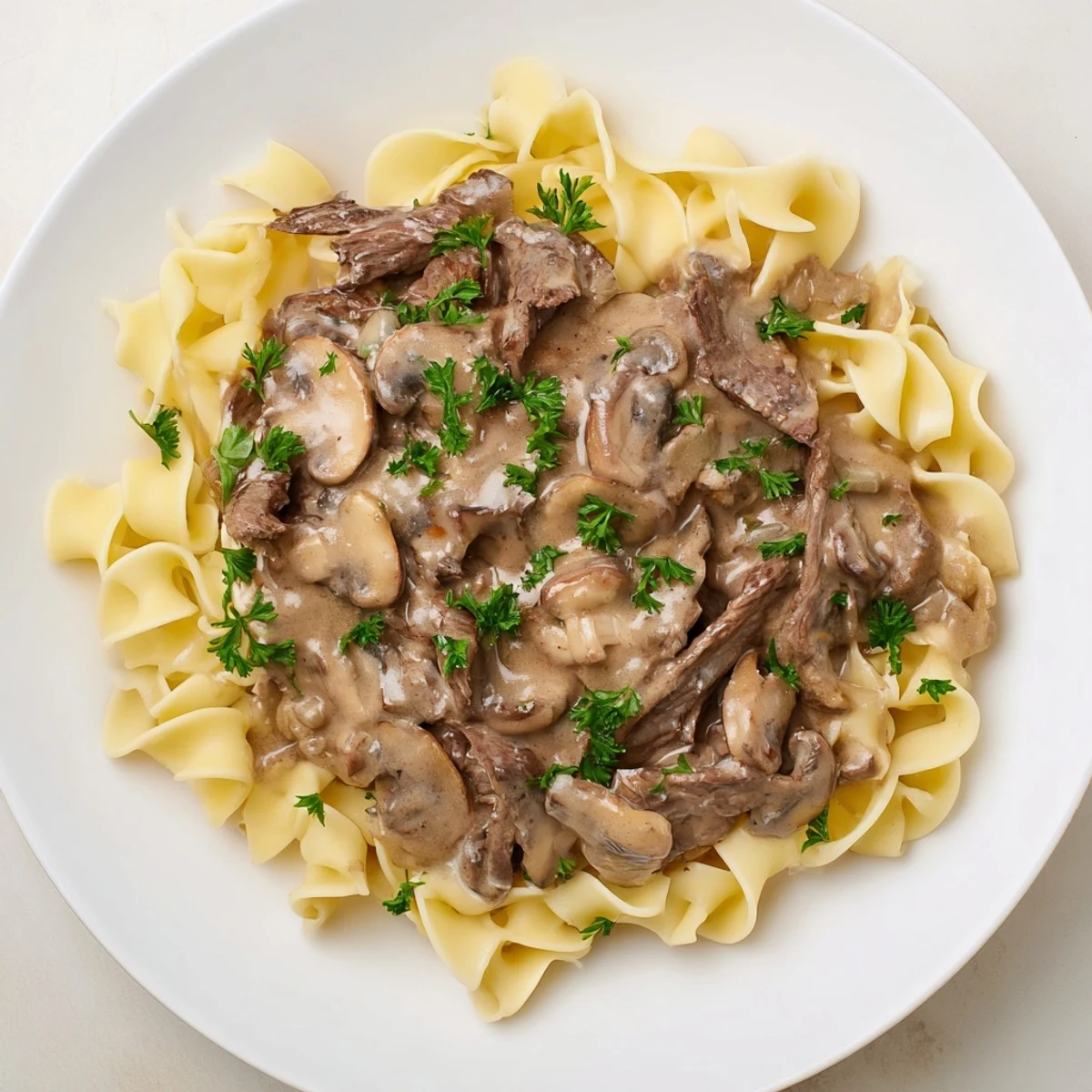 Hearty skillet of Beef Stroganoff with Mushroom Gravy over egg noodles with onions and garlic.
