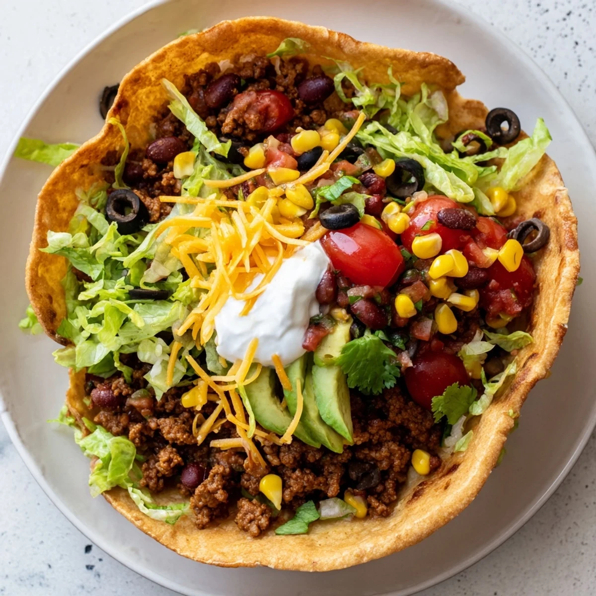 Crisp, golden homemade tortilla bowls filled with seasoned ground beef, black beans, and fresh salsa, topped with shredded cheddar and creamy avocado.