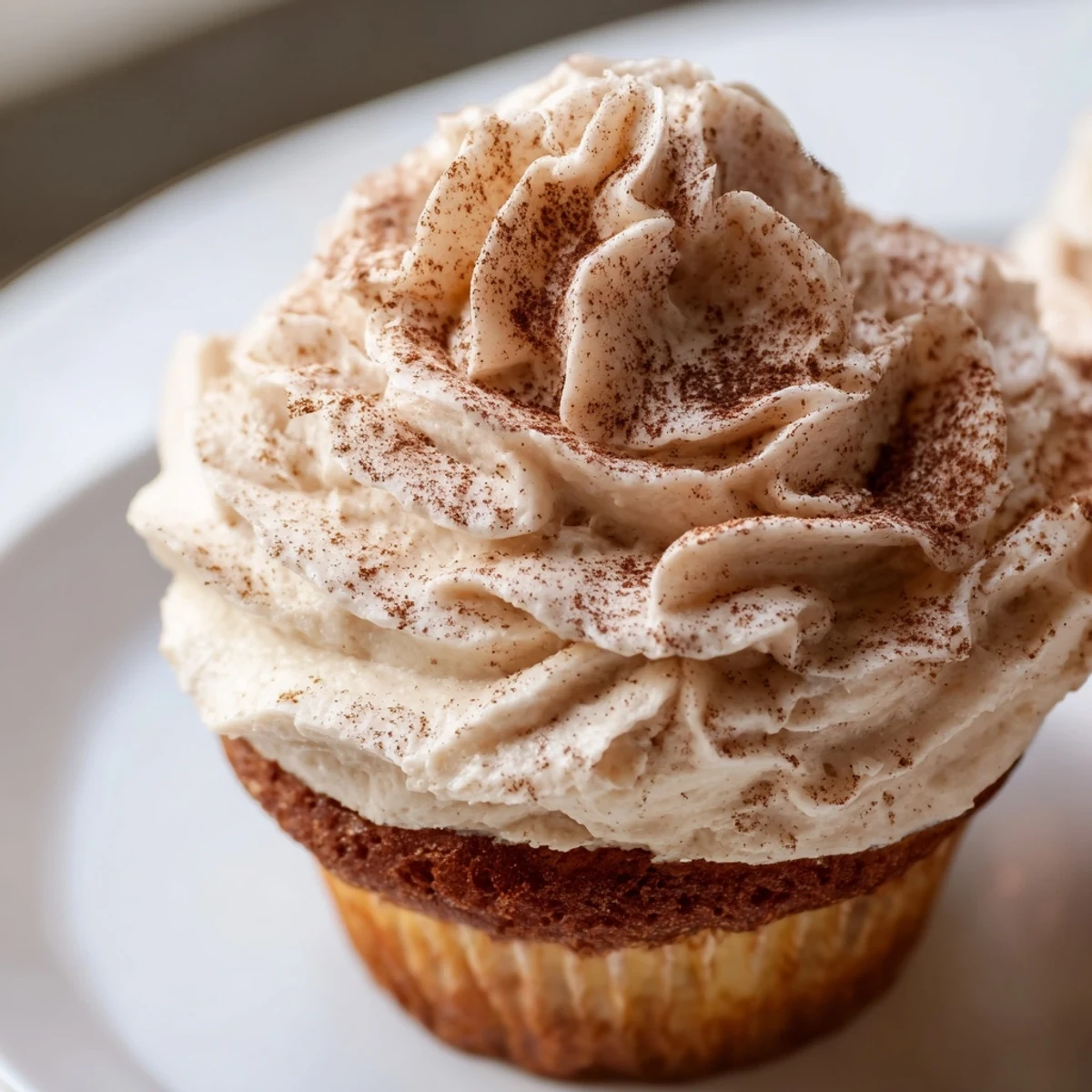 Twelve Irish Cream Cupcakes sit in a baking tin, their vanilla crumb slightly domed and golden with delicate cracks on top.  