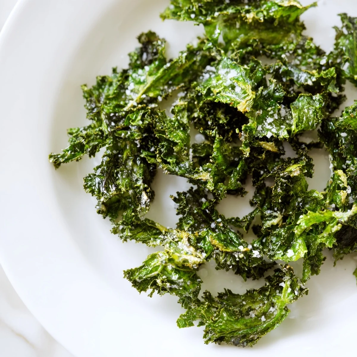 Crispy green kale chips with sea salt, baked golden on parchment, served warm in a rustic bowl.  