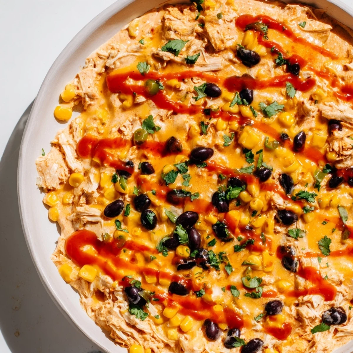 Fresh cilantro and diced jalapeños top this creamy, warm Chicken Enchilada Dip, perfect for a party appetizer.