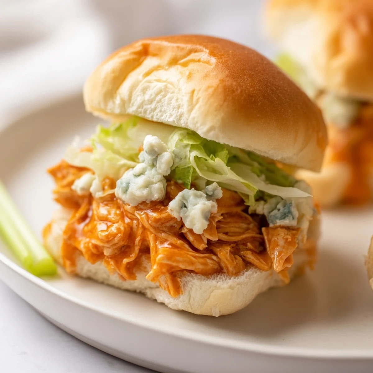 Freshly toasted slider buns piled high with tender buffalo chicken, topped with a generous drizzle of creamy blue cheese sauce.