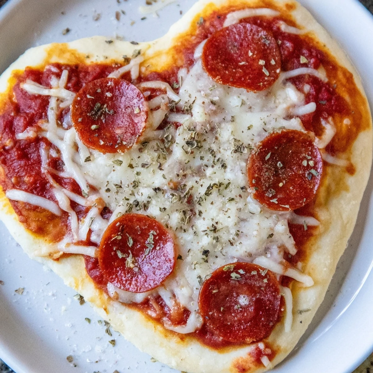 Close-up of a Heart Shaped Pepperoni Pizza with Beef Pepperoni, featuring melted mozzarella and fresh basil garnish on a rustic board.