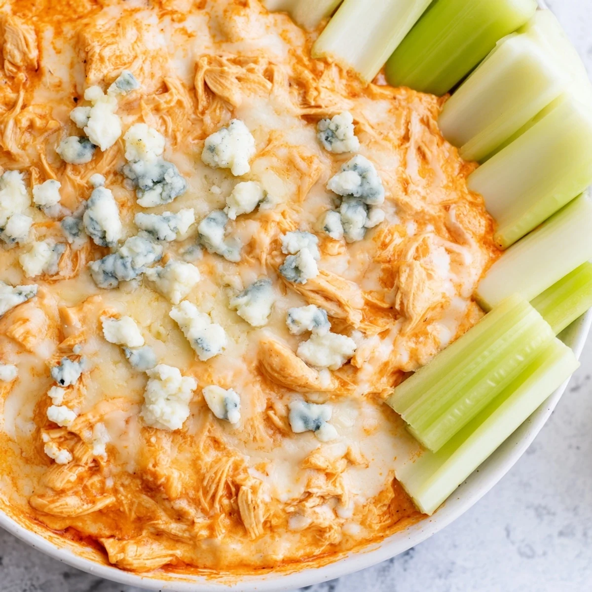 Bubbling Spicy Buffalo Chicken Dip from the oven, garnished with fresh herbs and celery sticks for a classic pairing.