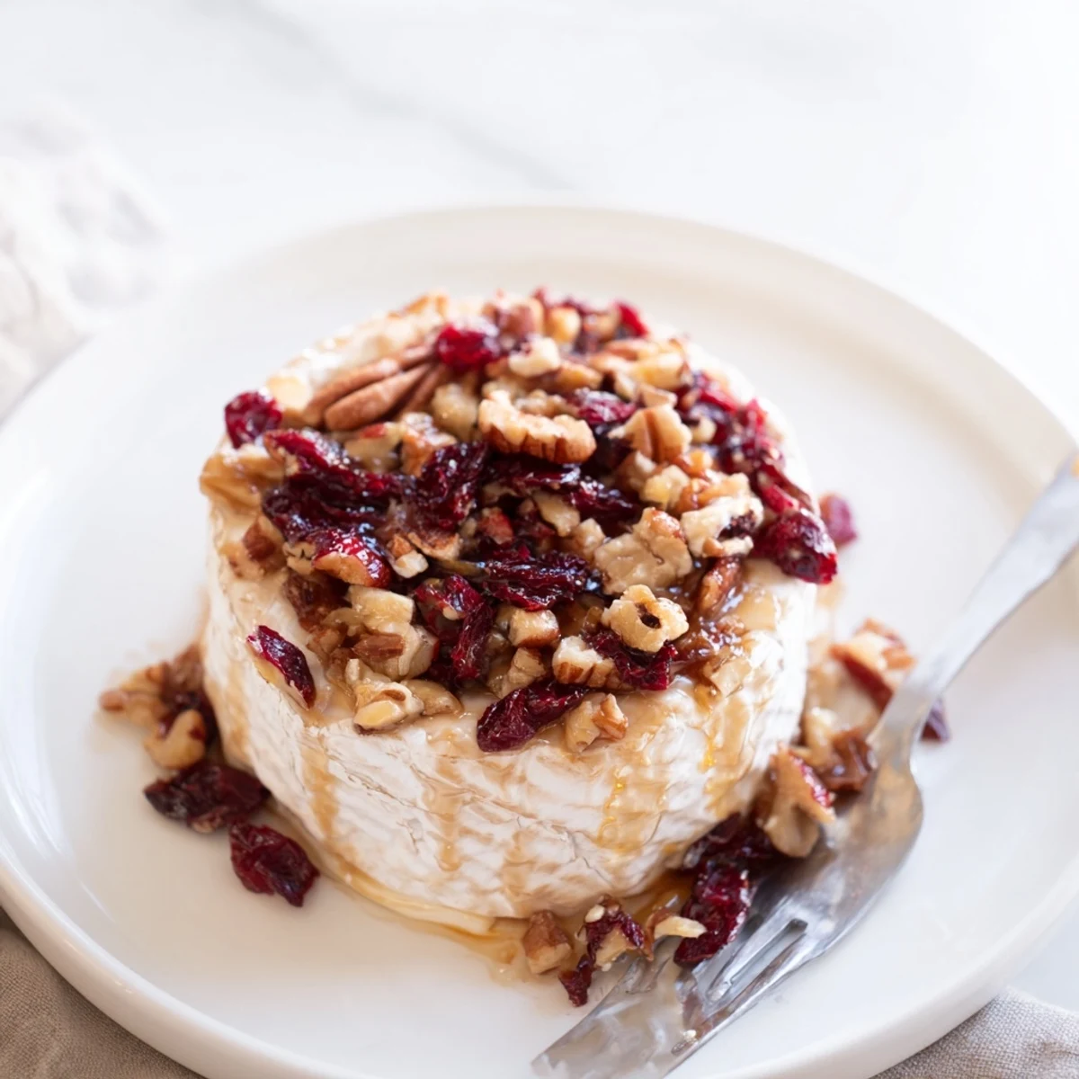 Fresh cranberries and pecans garnish the gooey, melted cheese of the Baked Brie with Cranberry and Pecan Topping.