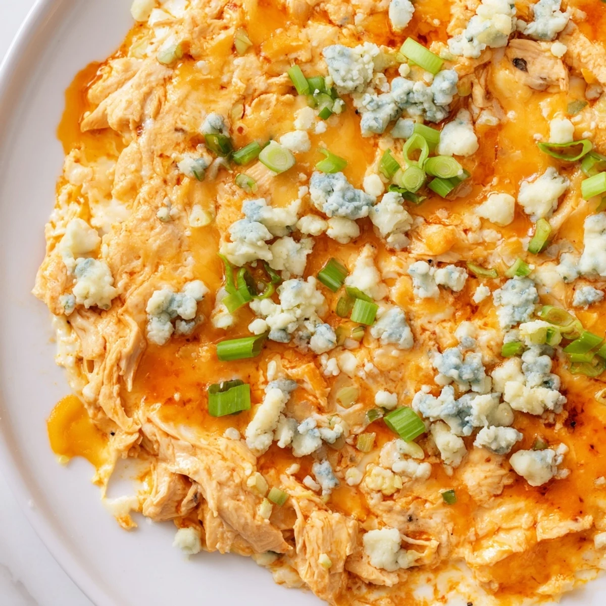 Spicy Keto Buffalo Chicken Dip garnished with green onions and blue cheese crumbles.  