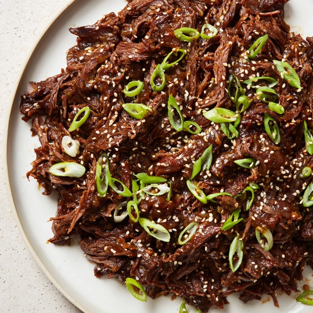 Slow Cooker Korean Beef piled into crisp lettuce wraps, garnished with sesame seeds and bright red chili slices for crunch.