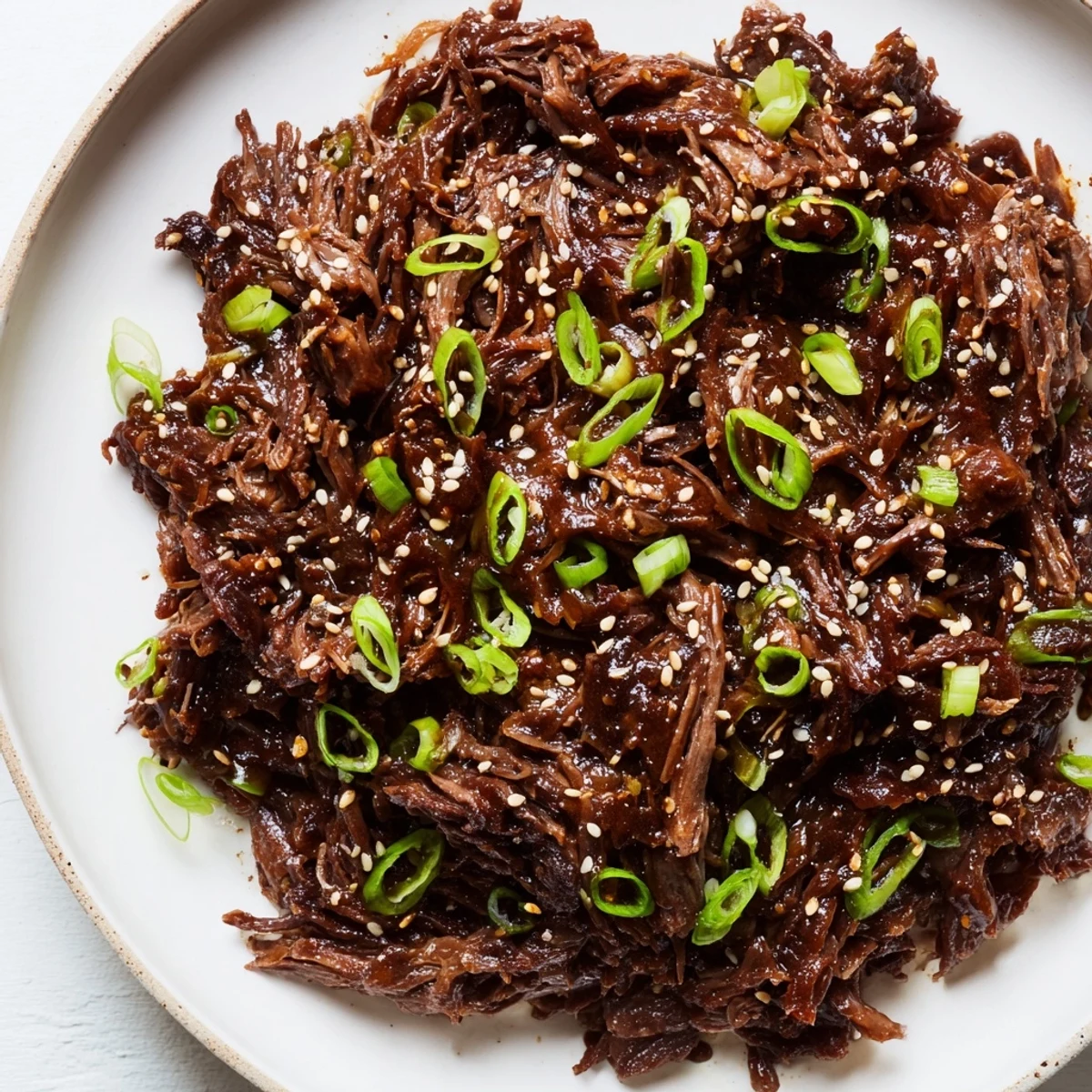 A hearty serving of Slow Cooker Korean Beef atop steamed rice, with a side of kimchi and chopsticks ready to eat.