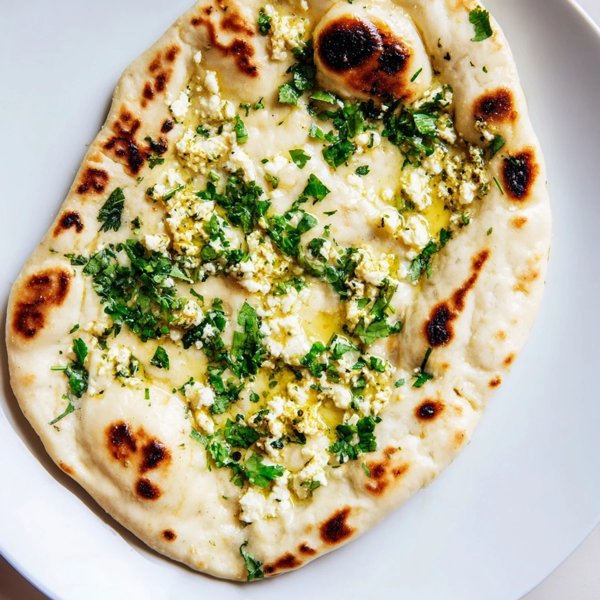 Soft and pillowy Cottage Cheese Garlic Naan stacked on a plate, ready to serve with a rich curry dish.