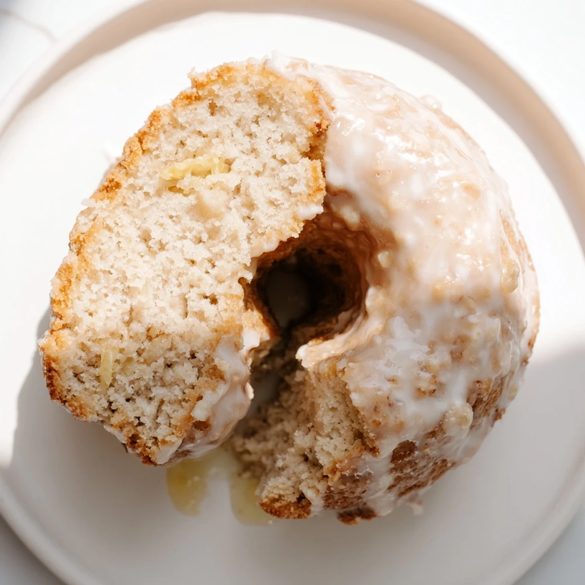 Golden Baked Banana Bread Donuts resting on a wire rack, lightly glazed and speckled with ripe banana bits for a moist, tender bite.  