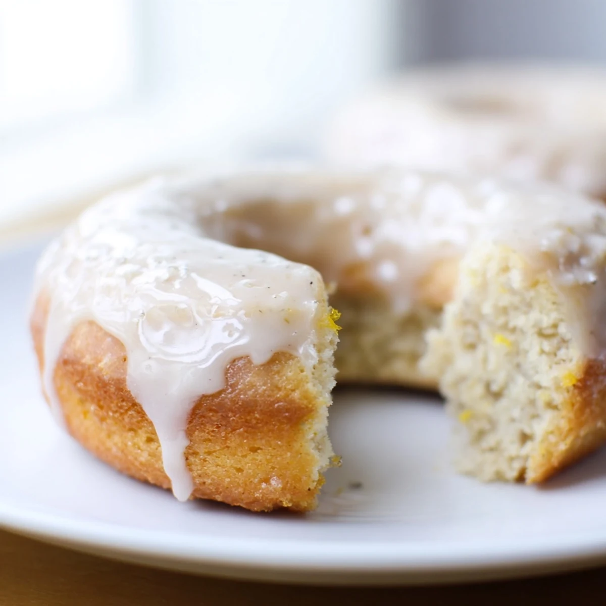 Twelve freshly baked Baked Banana Bread donuts arranged on a platter, finished with a sweet vanilla glaze and ready to serve.