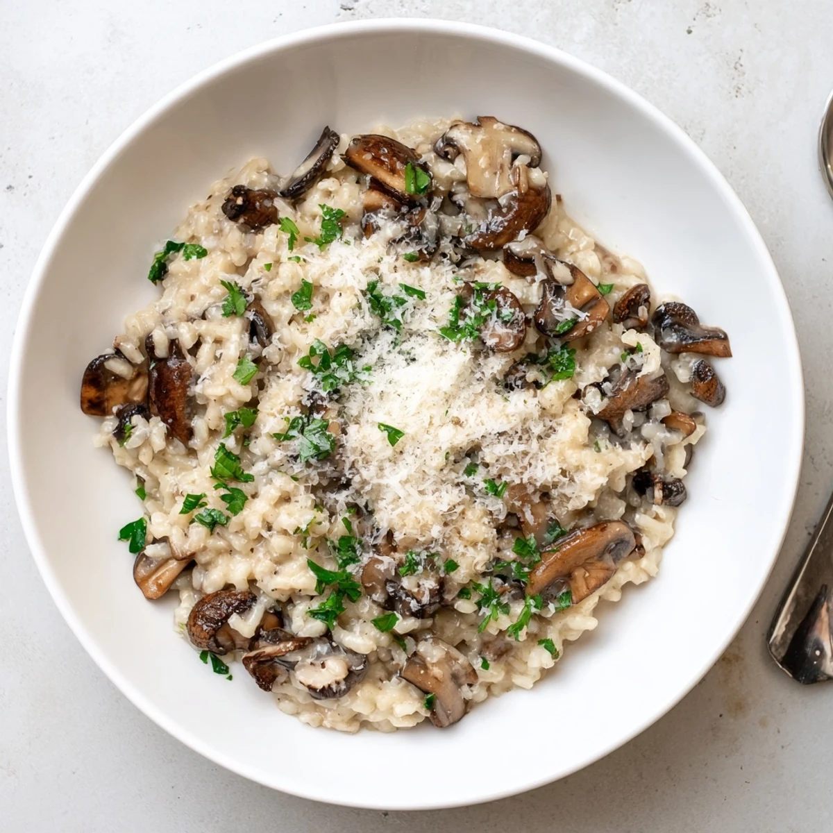 Creamy mushroom risotto steams in a rustic ceramic bowl, garnished with fresh parsley and extra grated Parmesan cheese.