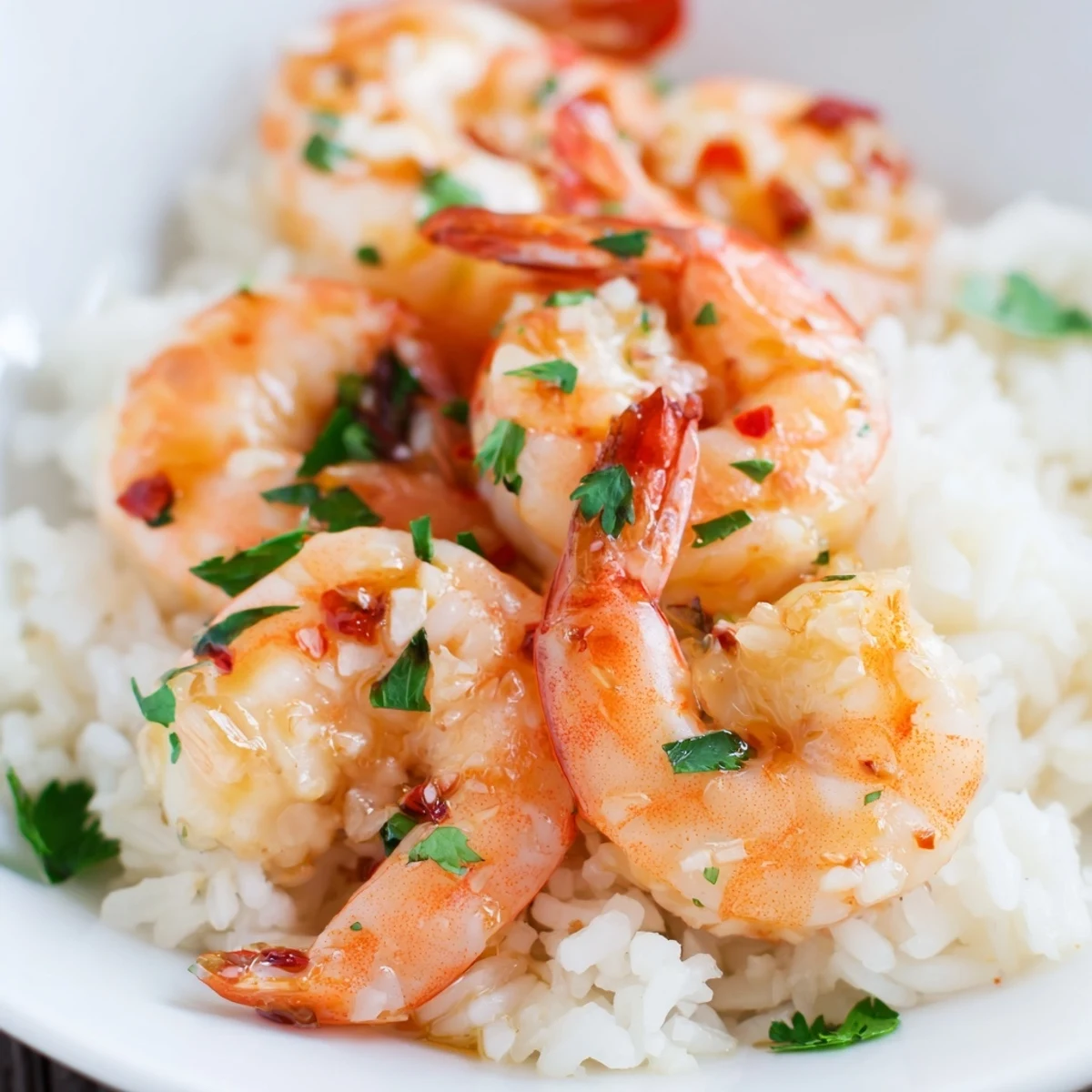 A close-up of juicy marinated shrimp with bright red chili, served alongside fluffy white coconut rice.
