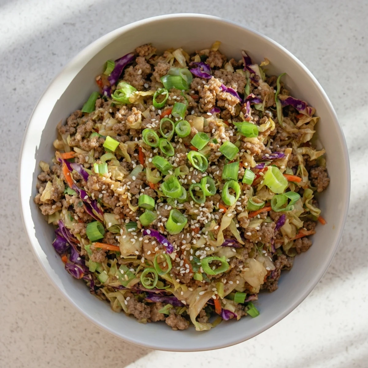 An overhead view of a colorful Egg Roll In A Bowl served in a white bowl, with steam rising from the fresh pork and vegetable stir-fry.