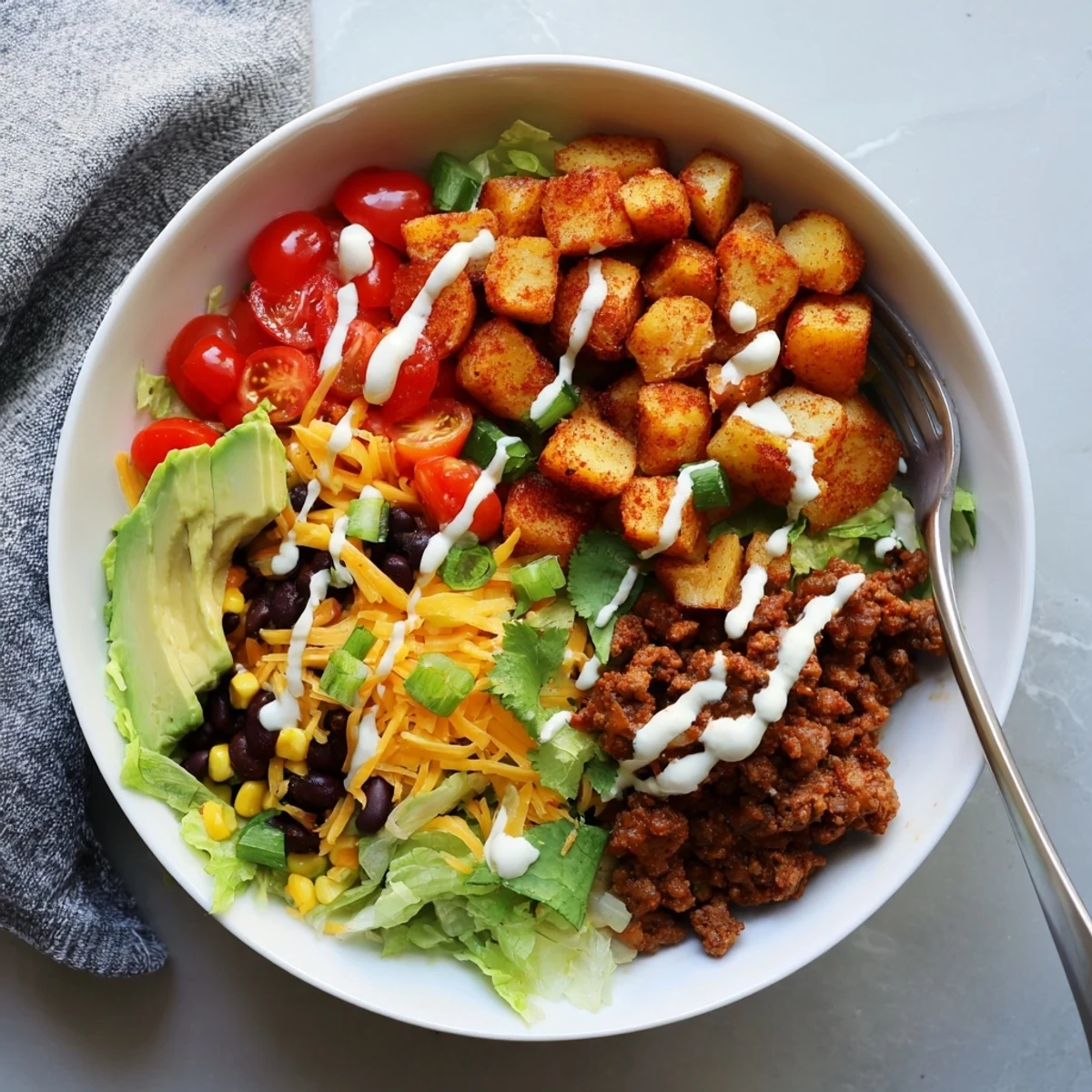 A vibrant Loaded Potato Taco Bowl served in a rustic bowl with a drizzle of zesty crema.