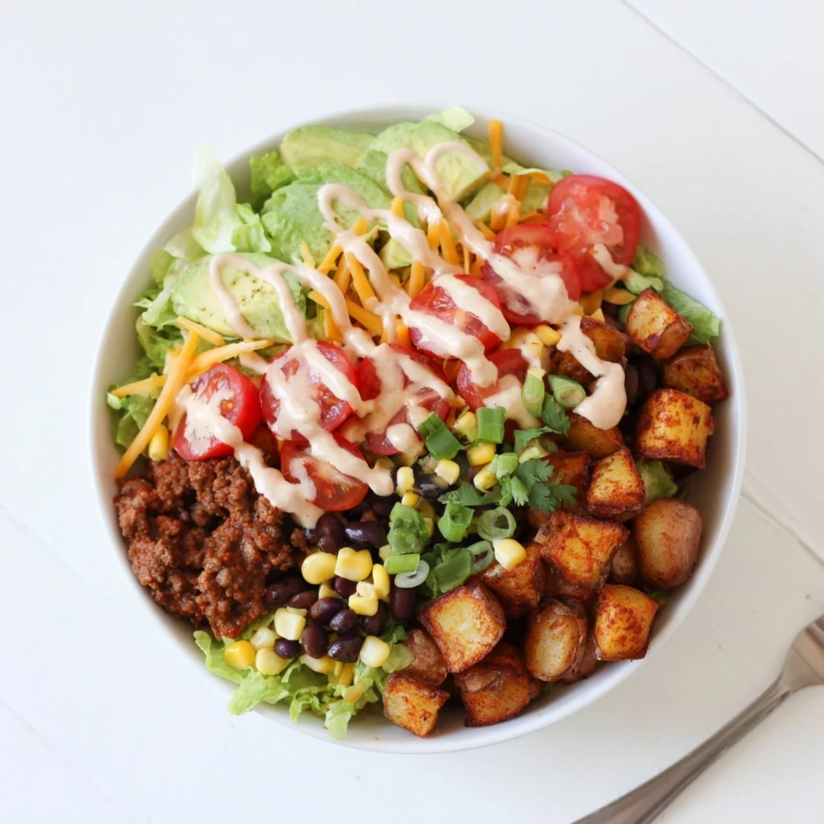 Overhead view of a Loaded Potato Taco Bowl topped with melted cheddar, corn, and fresh cilantro garnish.