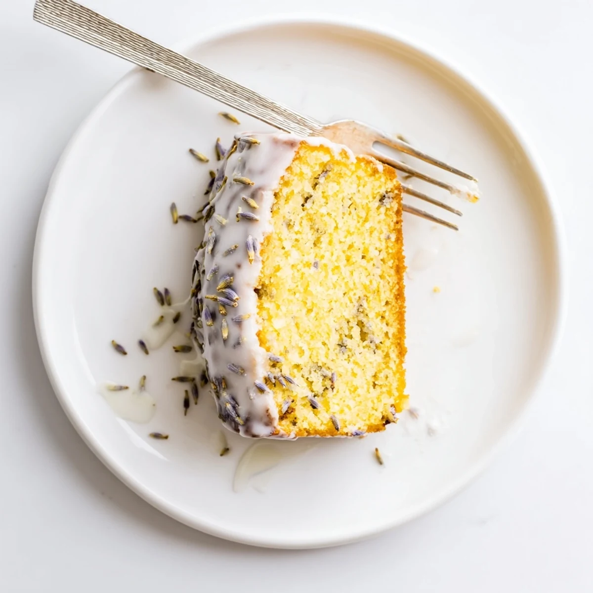 A close-up of the Lemon Lavender Cake with a shiny lemon glaze and dried lavender buds garnish, perfect for an elegant dessert.