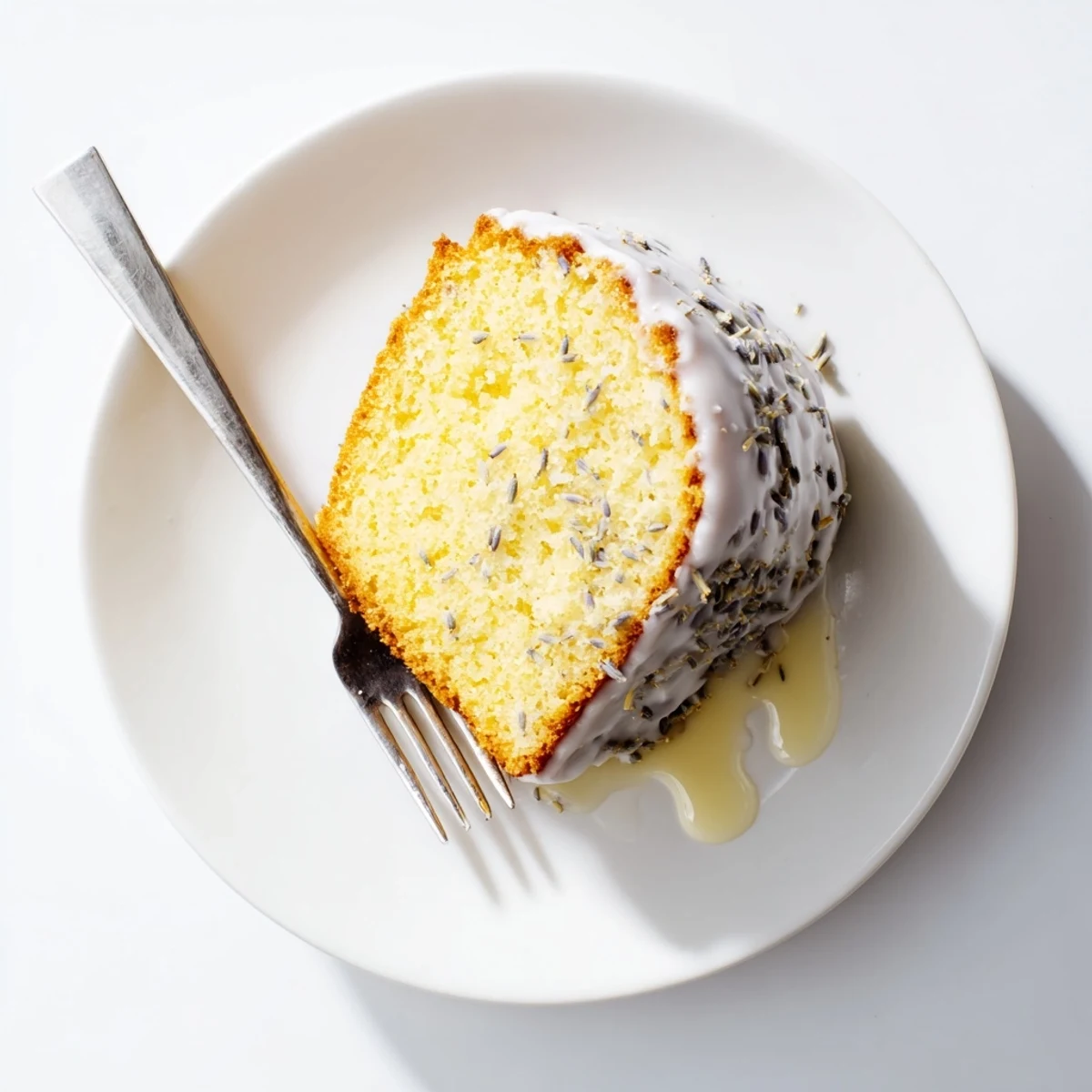 Freshly glazed Lemon Lavender Cake displayed on a white plate with lemon slices and lavender sprigs for a stunning presentation.