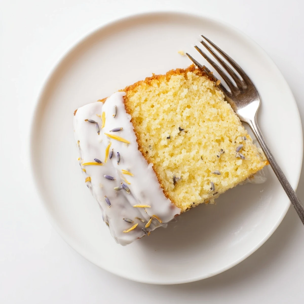 This moist Lemon Lavender Cake slice reveals a tender crumb with lemon zest, paired with a cup of Earl Grey tea.