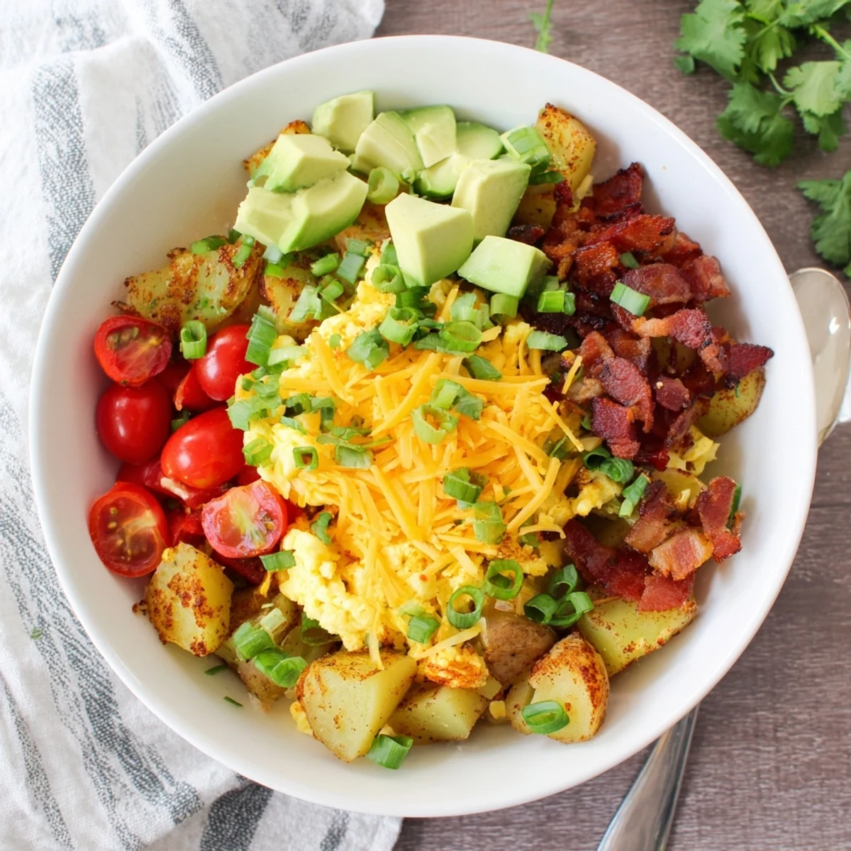 The Loaded Breakfast Bowl showcases diced avocado, cherry tomatoes, and green onions on a hearty American breakfast spread.
