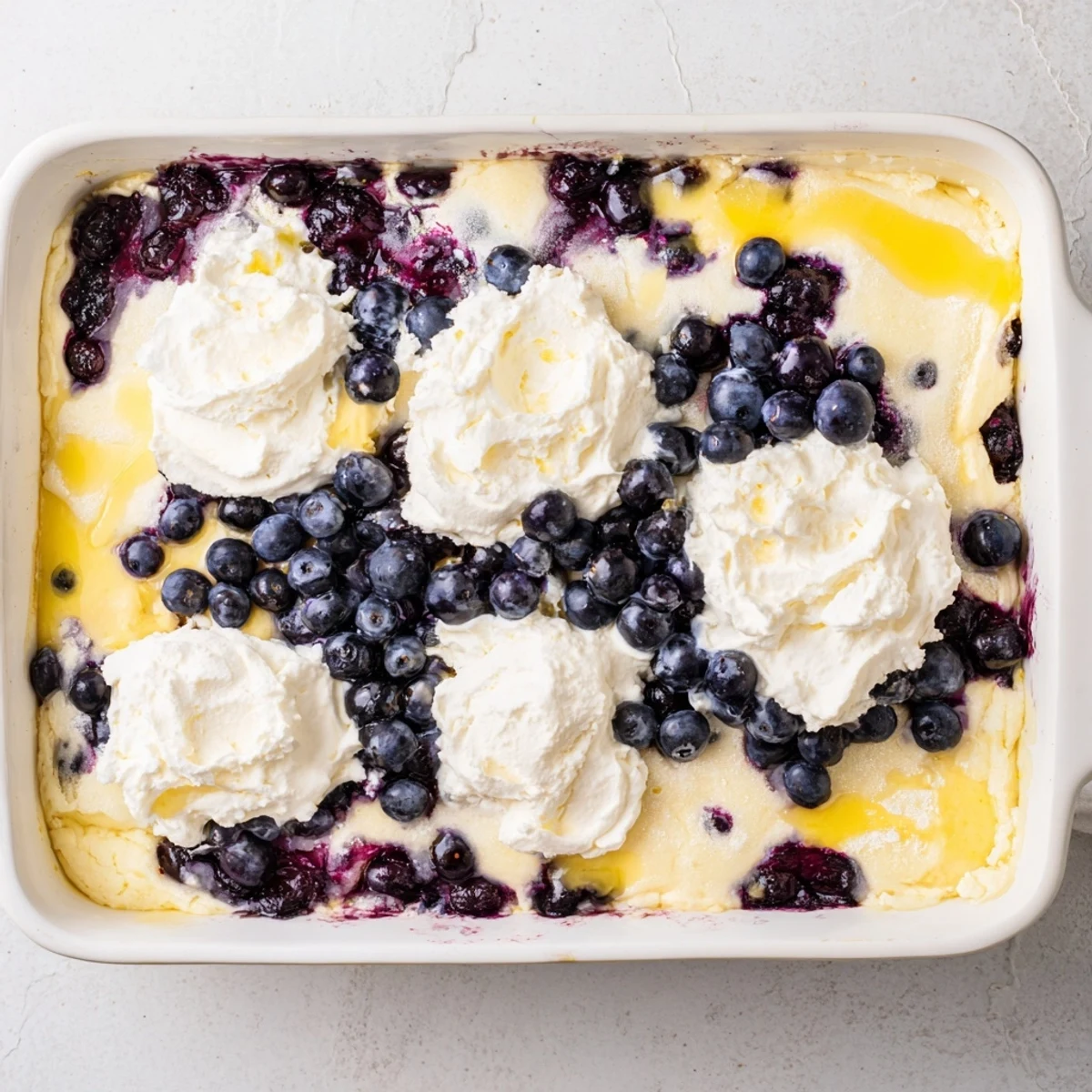 Bubbling 9x13 pan of lemon blueberry cheesecake dump cake with golden brown crumbly topping