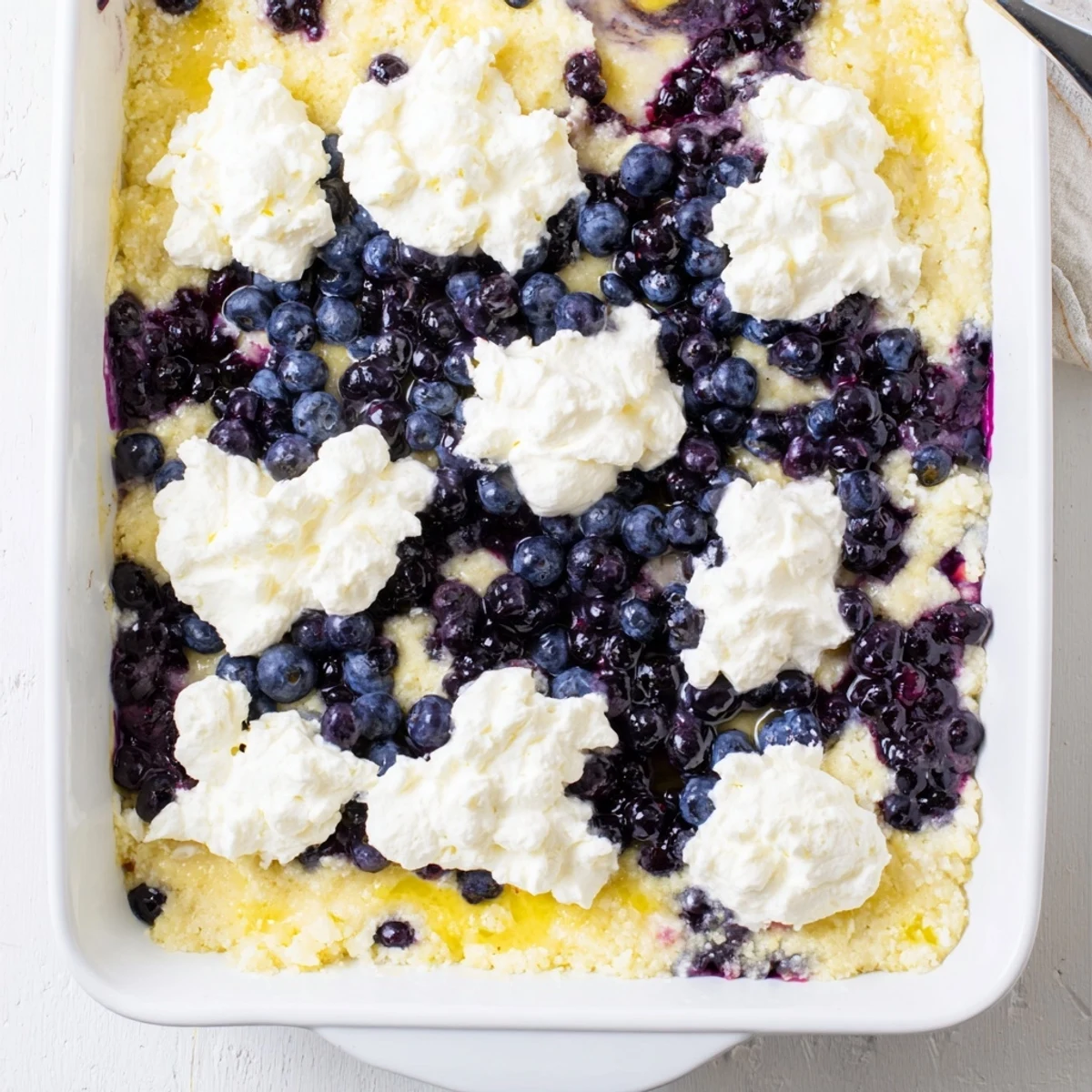 Creamy cheesecake layered blueberry lemon dump cake served warm with melting vanilla ice cream