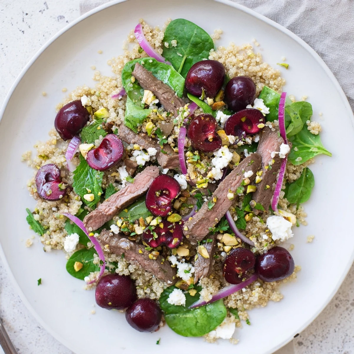 Mediterranean-style cherry quinoa salad with tender lamb strips, bright red cherries, and toasted nuts