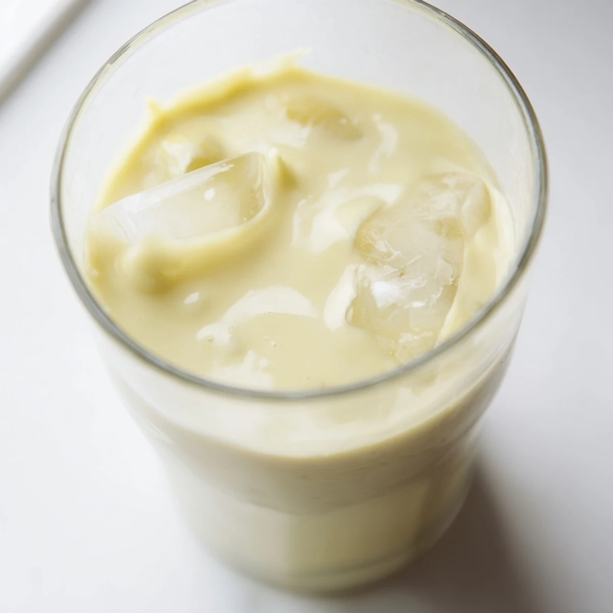Creamy durian smoothie poured into a chilled glass with ice cubes on top