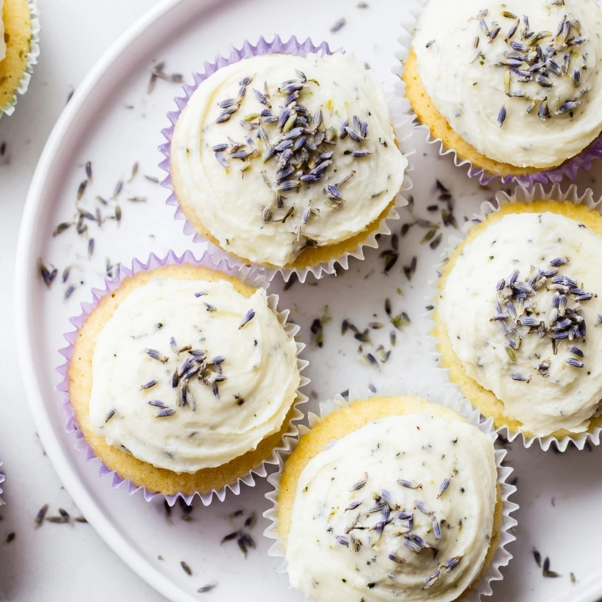 Fresh and fluffy lemon lavender cupcakes topped with creamy swirled frosting on a white plate