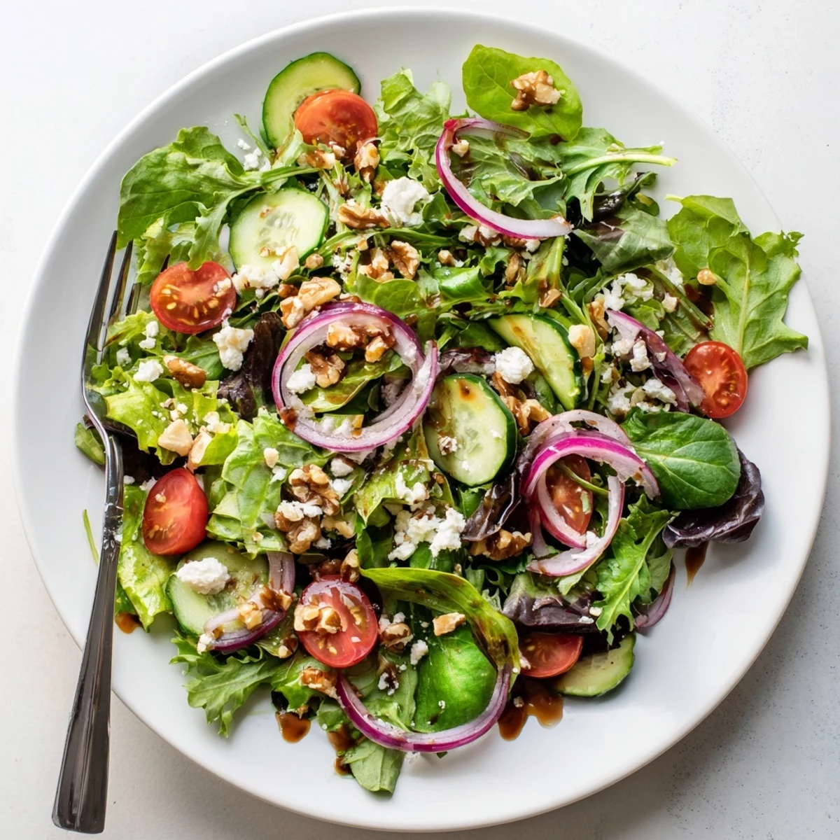 Fresh spring mix salad with balsamic honey dressing featuring crisp vegetables and crumbled feta