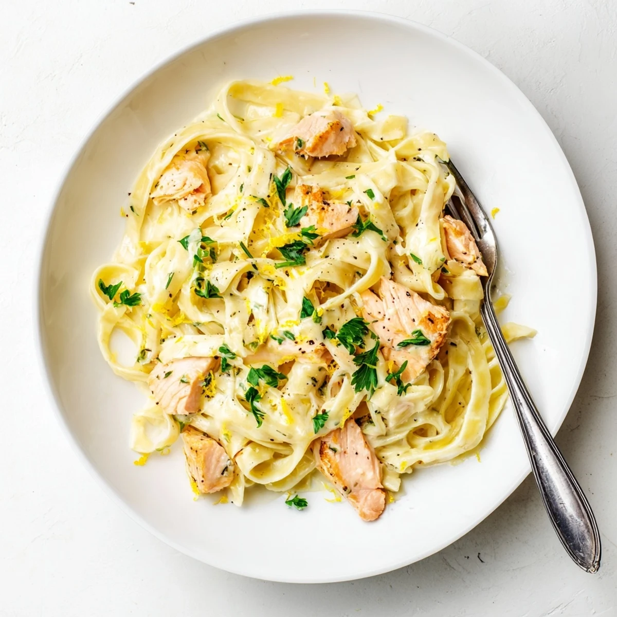 Golden seared salmon pieces rest atop creamy garlic butter fettuccine pasta with fresh parsley garnish