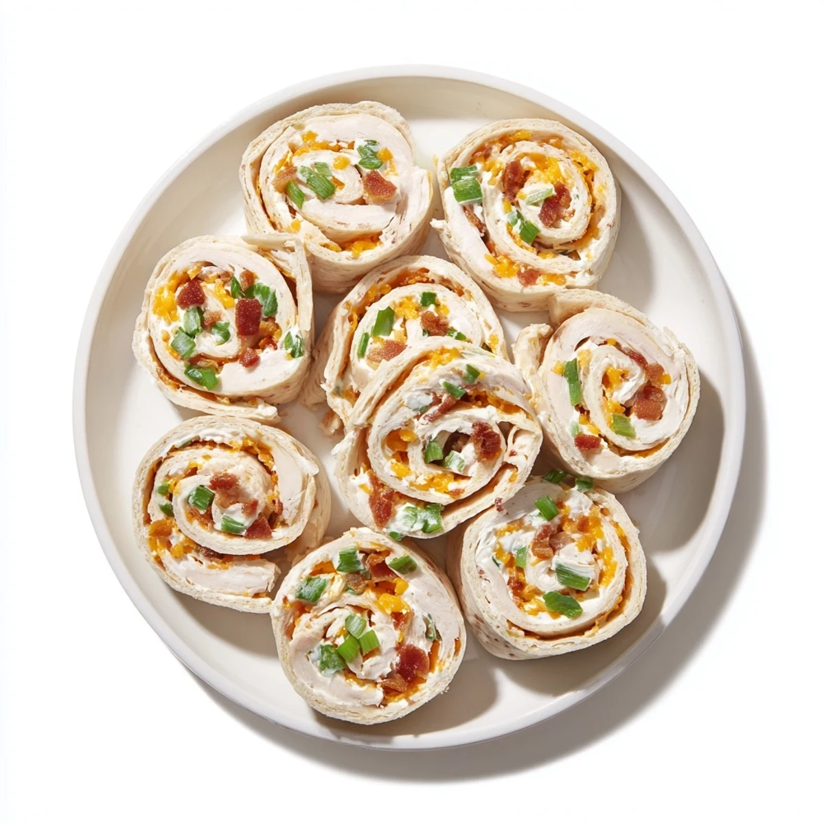 Appetizer platter showcasing sliced Crack Chicken Pinwheels with visible green onion bits and cheddar cheese