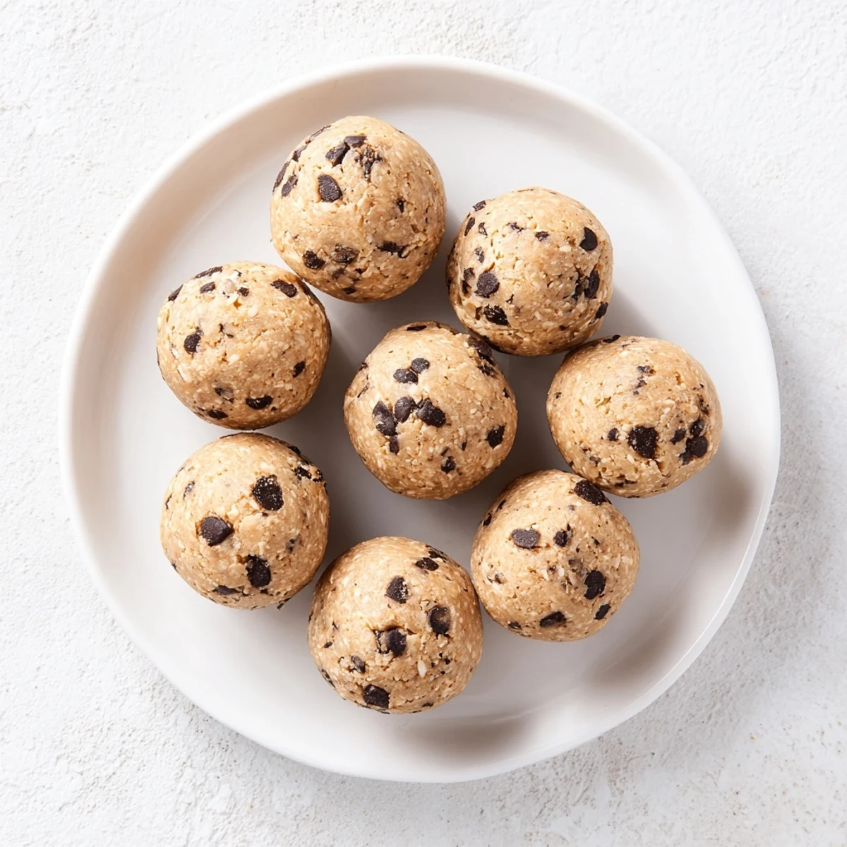 Protein-packed energy balls studded with melty dark chocolate chips on a white serving plate