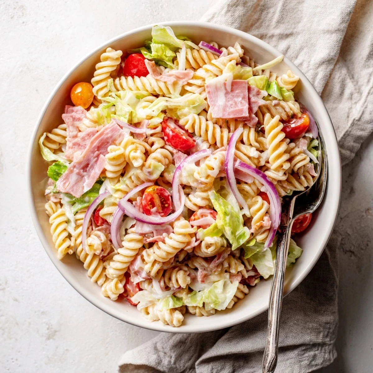 Hearty grinder pasta salad featuring tender penne tossed with ham, roasted red peppers, pepperoncini, and tangy mayonnaise vinaigrette
