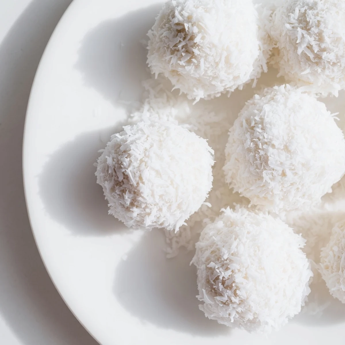 White coconut balls coated in fluffy shredded coconut arranged on a rustic wooden board for Easter