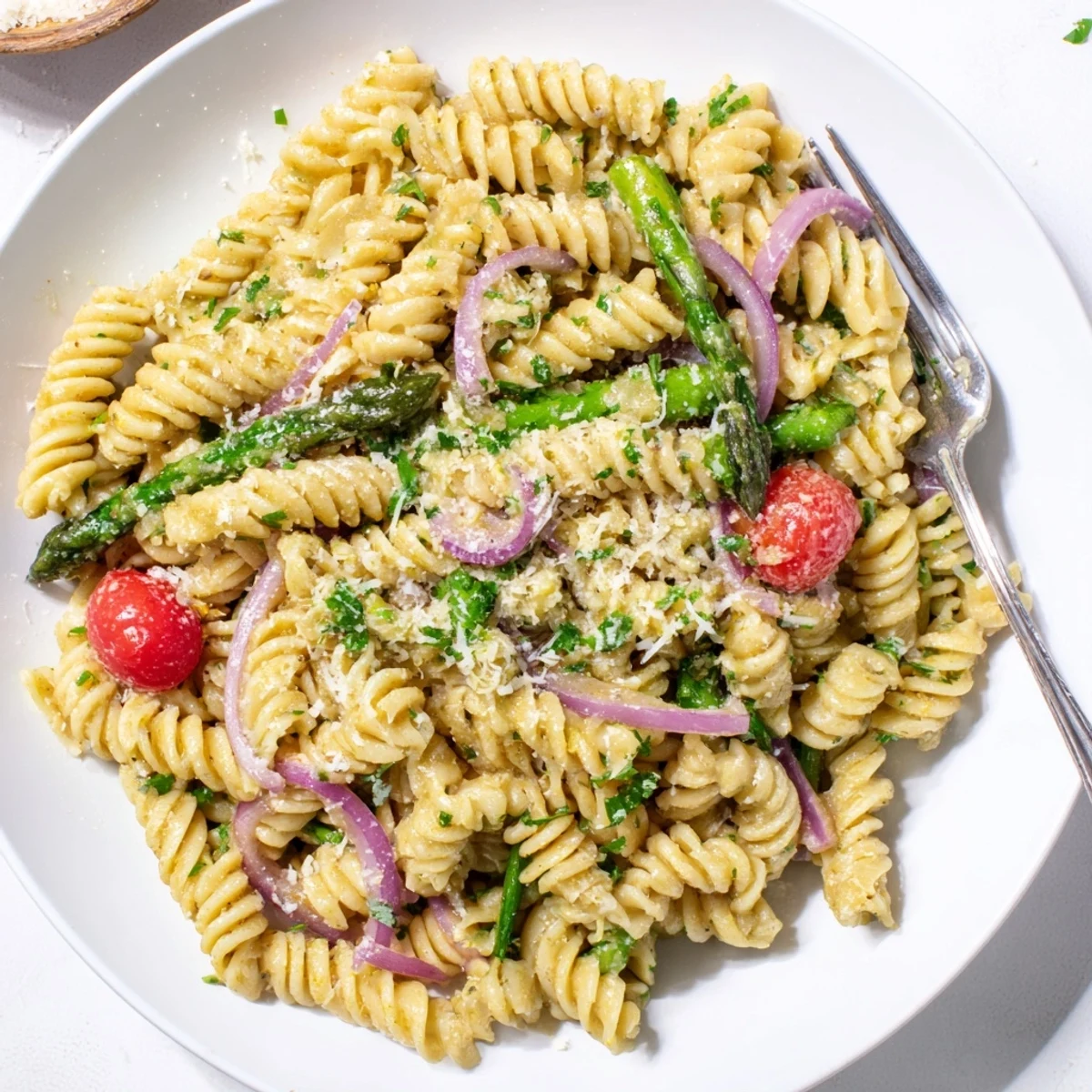 Bright lemon asparagus pasta salad featuring tender green stalks, cherry tomatoes, and fresh herbs in a light citrus dressing