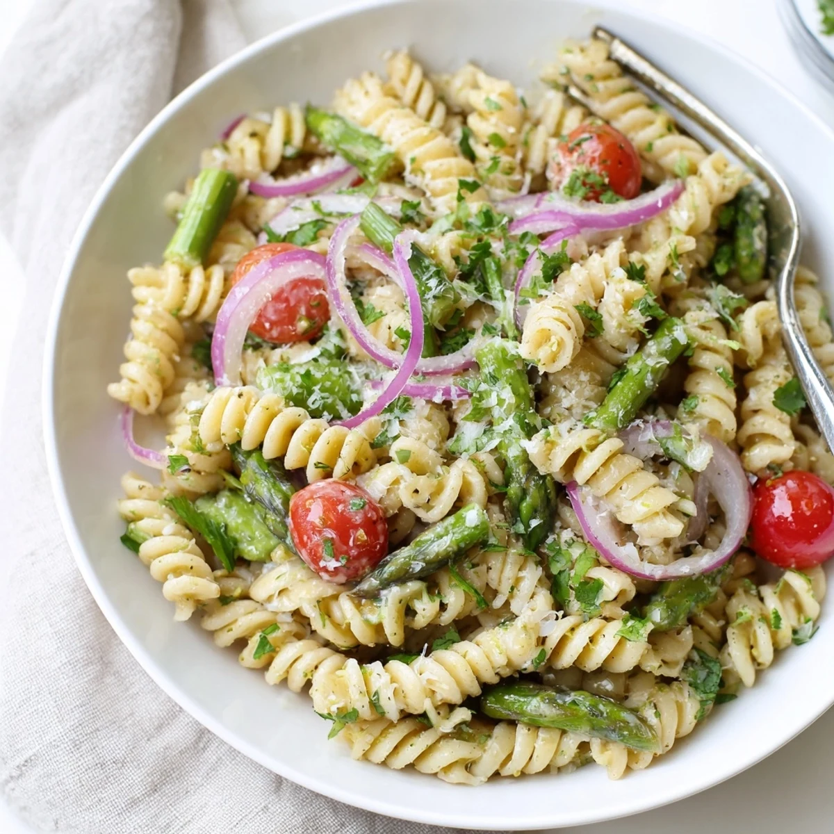 Vibrant lemon asparagus pasta salad bowl showcasing al dente pasta, roasted asparagus pieces, and colorful tomatoes