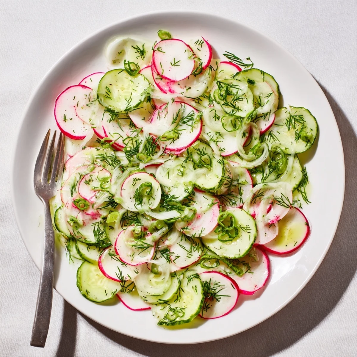 Colorful radish and cucumber salad tossed with fresh dill and light vinaigrette on a rustic wooden table
