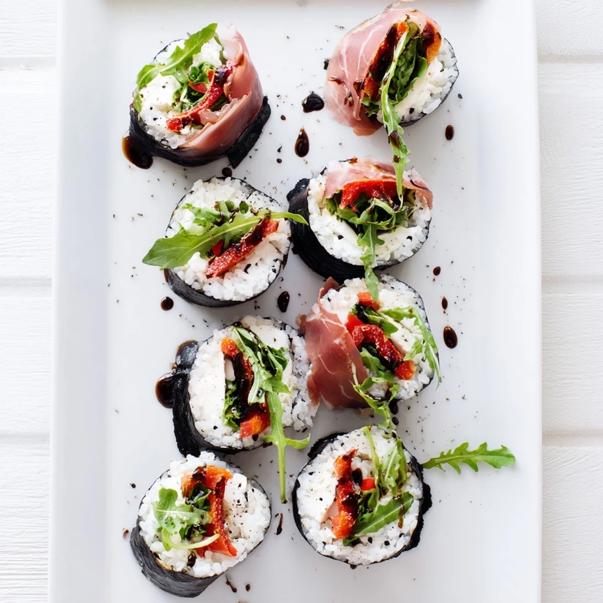Colorful Italian sushi rolls featuring prosciutto, mozzarella, and roasted peppers wrapped in nori