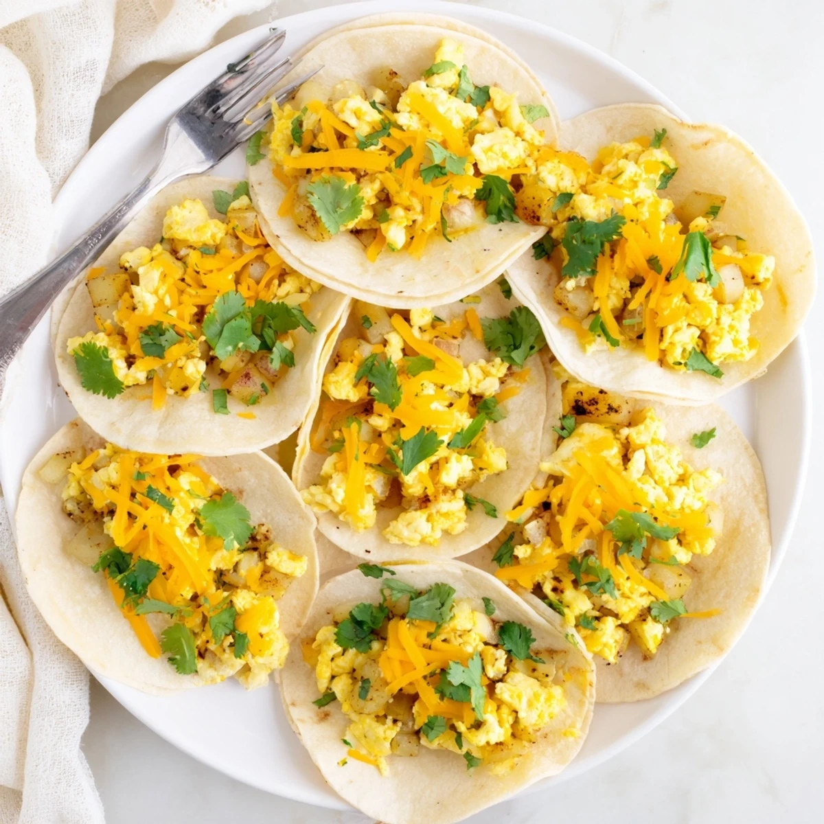 Crispy diced potatoes folded with seasoned eggs and gooey cheese inside these hearty potato egg cheese breakfast tacos