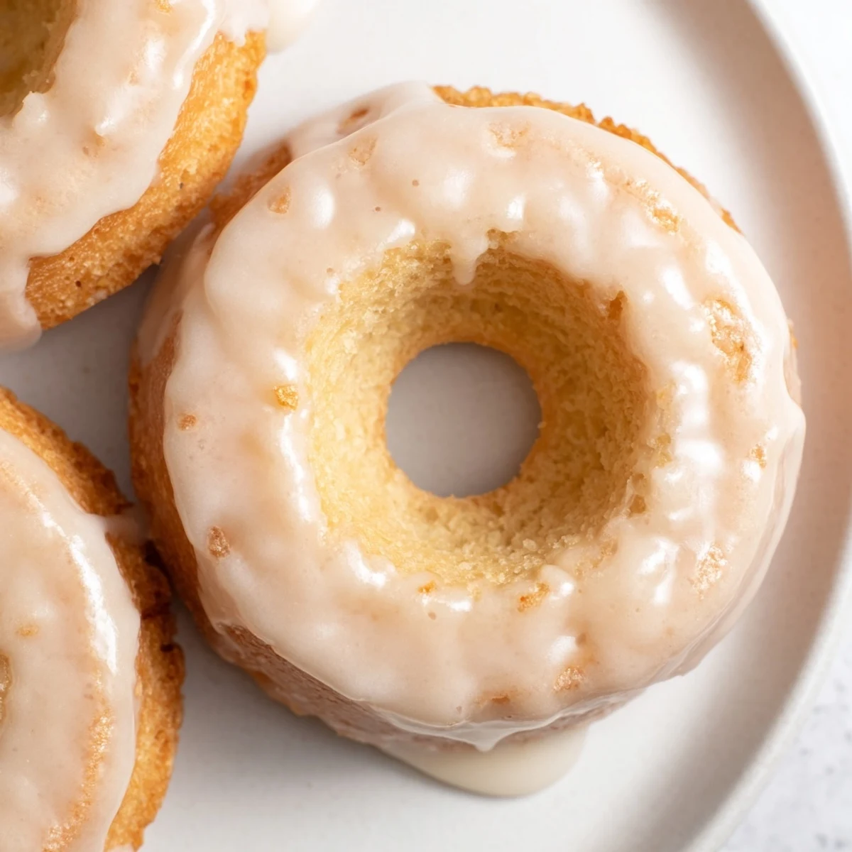 Golden Greek yogurt cake donuts topped with sweet vanilla glaze and colorful sprinkles on a white plate