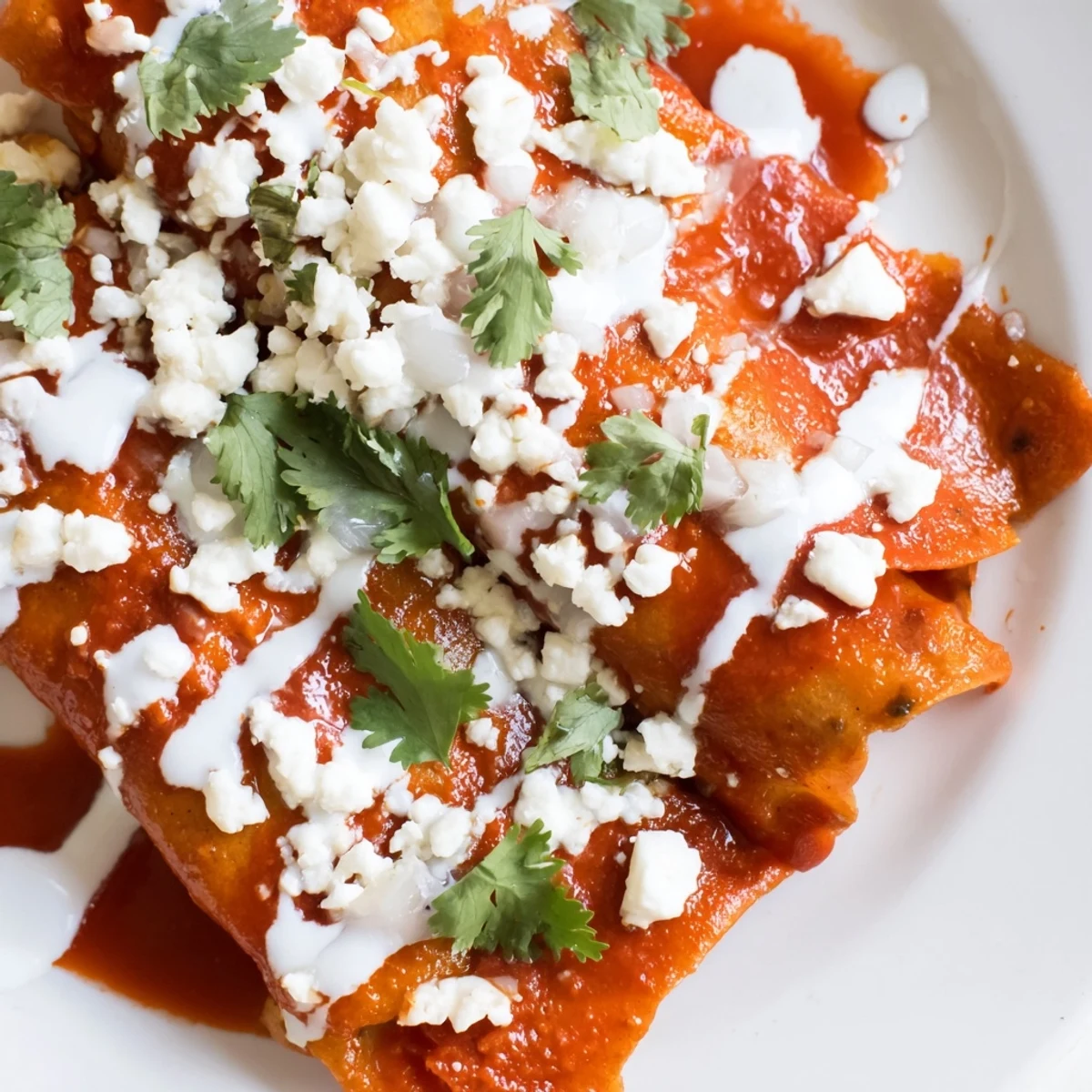Warm entomatadas folded and smothered in vibrant tomato salsa with creamy Mexican crema drizzle