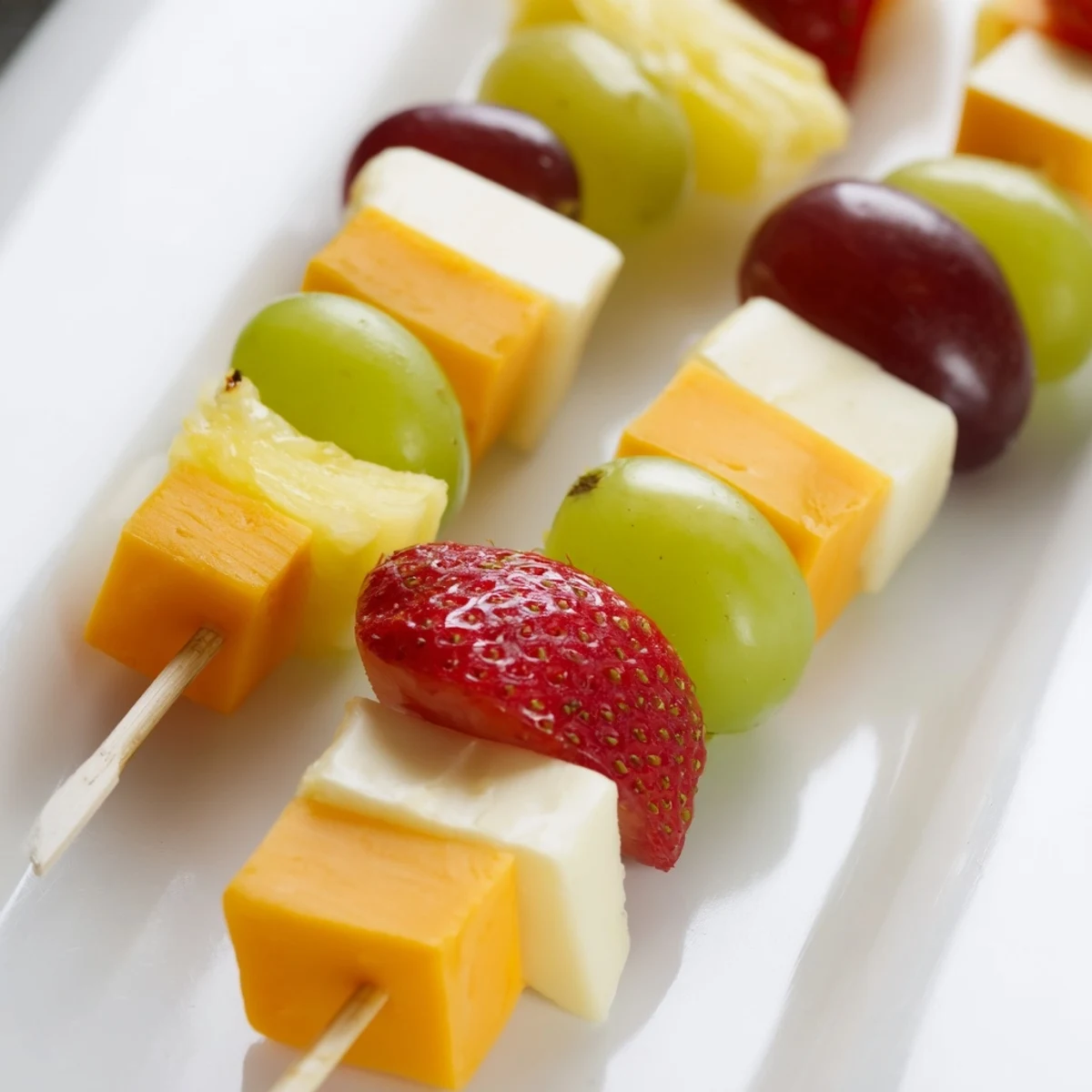 Fresh fruit and cheese kabobs featuring grapes strawberries pineapple and cheddar cubes