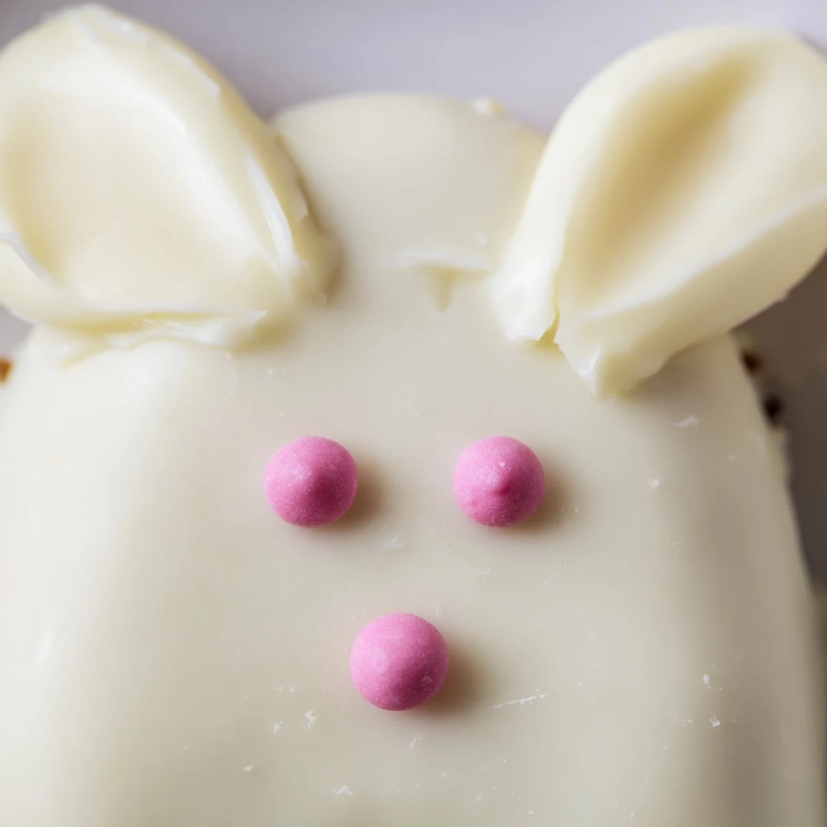Creamy white chocolate bunny cakesicles decorated with pink ears and festive sprinkles