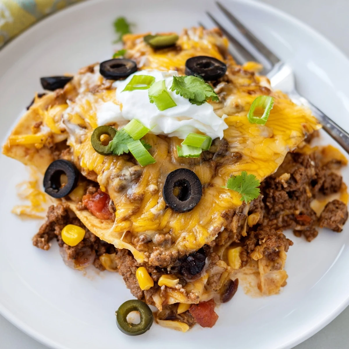 A steaming Cheesy Nacho Casserole slice on plate, paired with tangy salsa.
