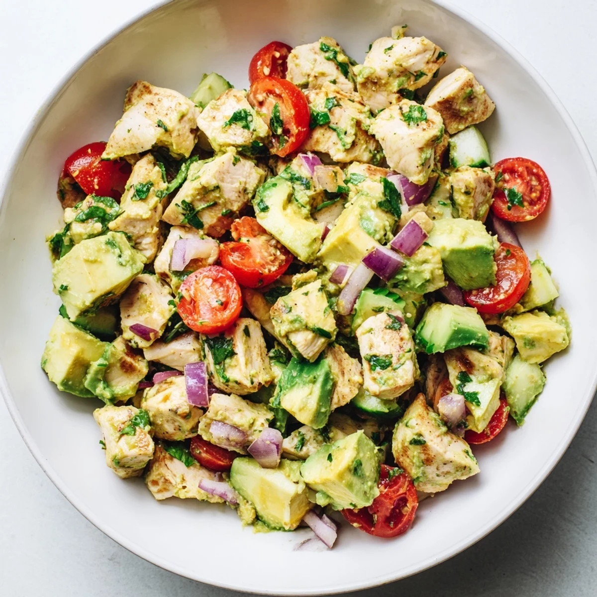 Light and nutritious healthy avocado chicken salad served in a bowl with bright garnishes