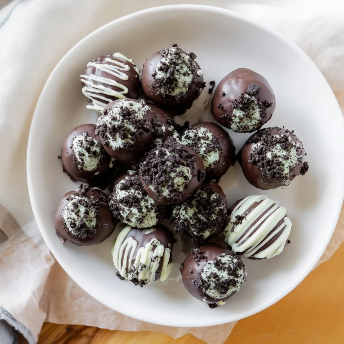 Bite-sized mint Oreo truffles coated in glossy dark chocolate with crushed cookie garnish