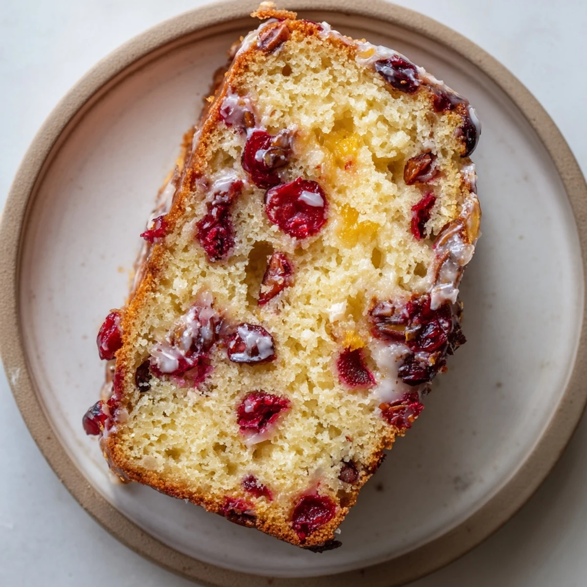 Sliced Cranberry Orange Bread stacked with butter melting, tart berries visible  
