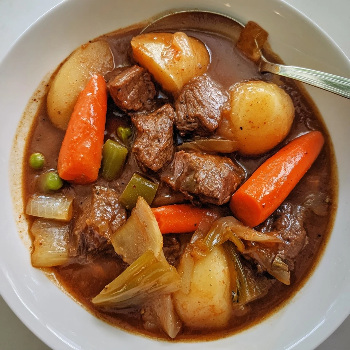 Hearty Beef Stew ladled over buttered noodles with fragrant thyme and bay leaves