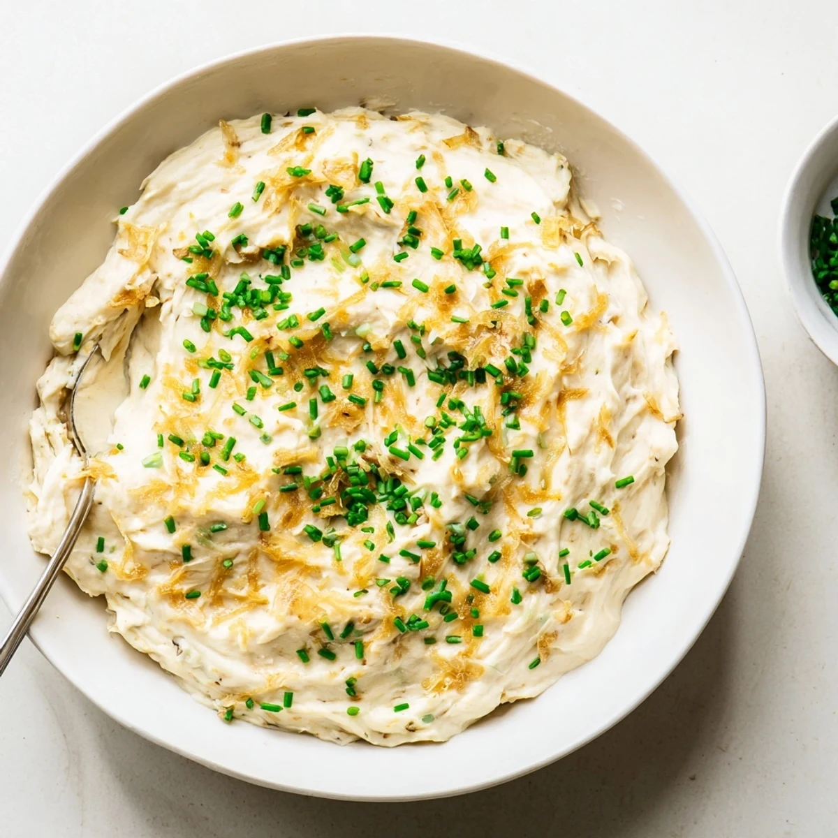 Creamy French onion dip topped with golden caramelized onions and fresh green onions garnish